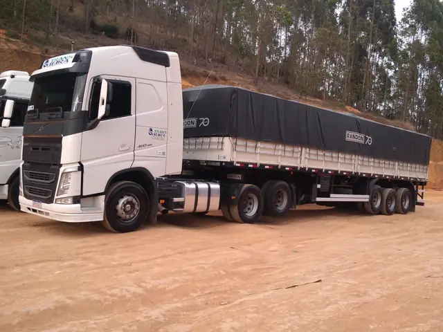 Caminhão branco da Transvieira com carreta graneleira lonada