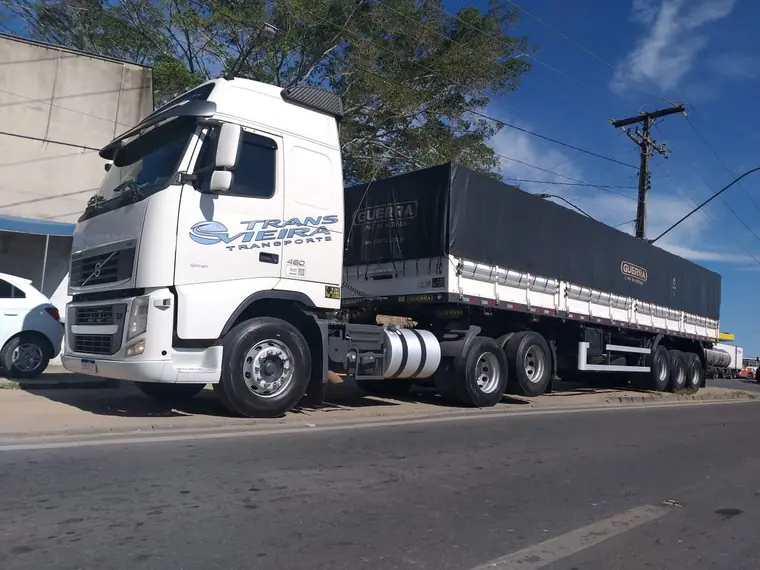 Caminhão branco da Transvieira com carreta lonada estacionado na beira de uma rua